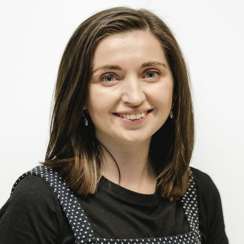 Beth looking at the camera directly and smiling against a white background