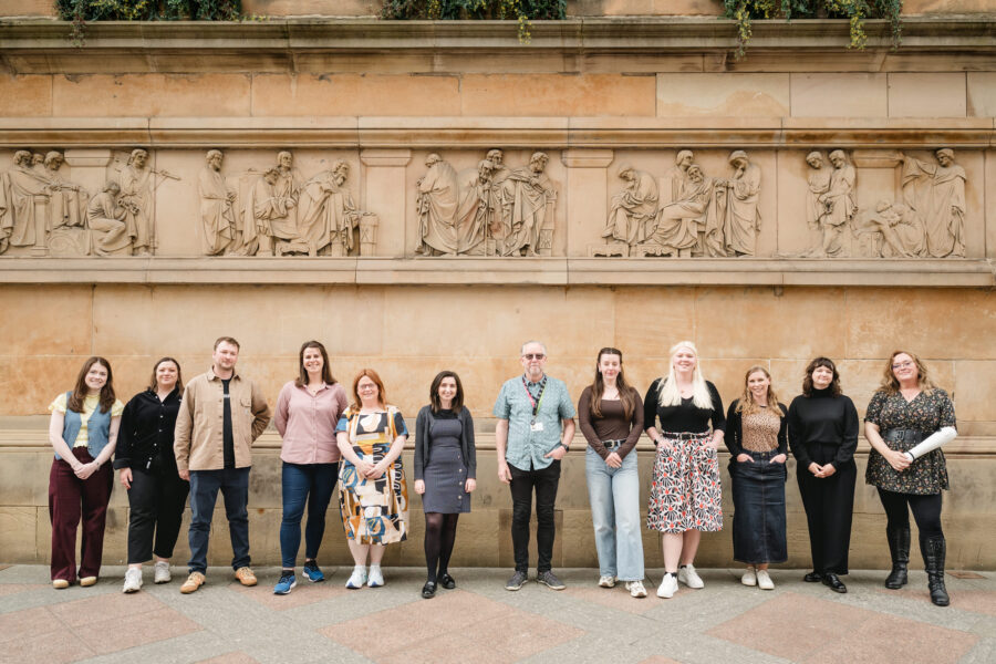 Heritage Network staff team standing in a line and facing the camera in front of a heritage building.