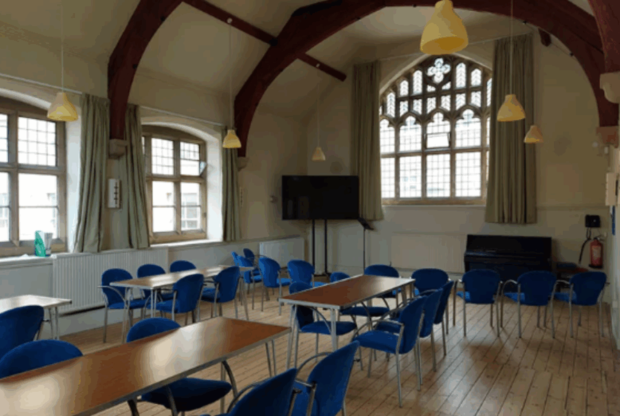 Photograph of the interior of the de Lacy Centre, a rooms with ornate windows and wooden beams, set out like a classroom.