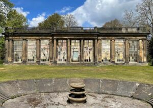 The Camellia House before restoration, derelict. an empty water fountain stands in front of the building.