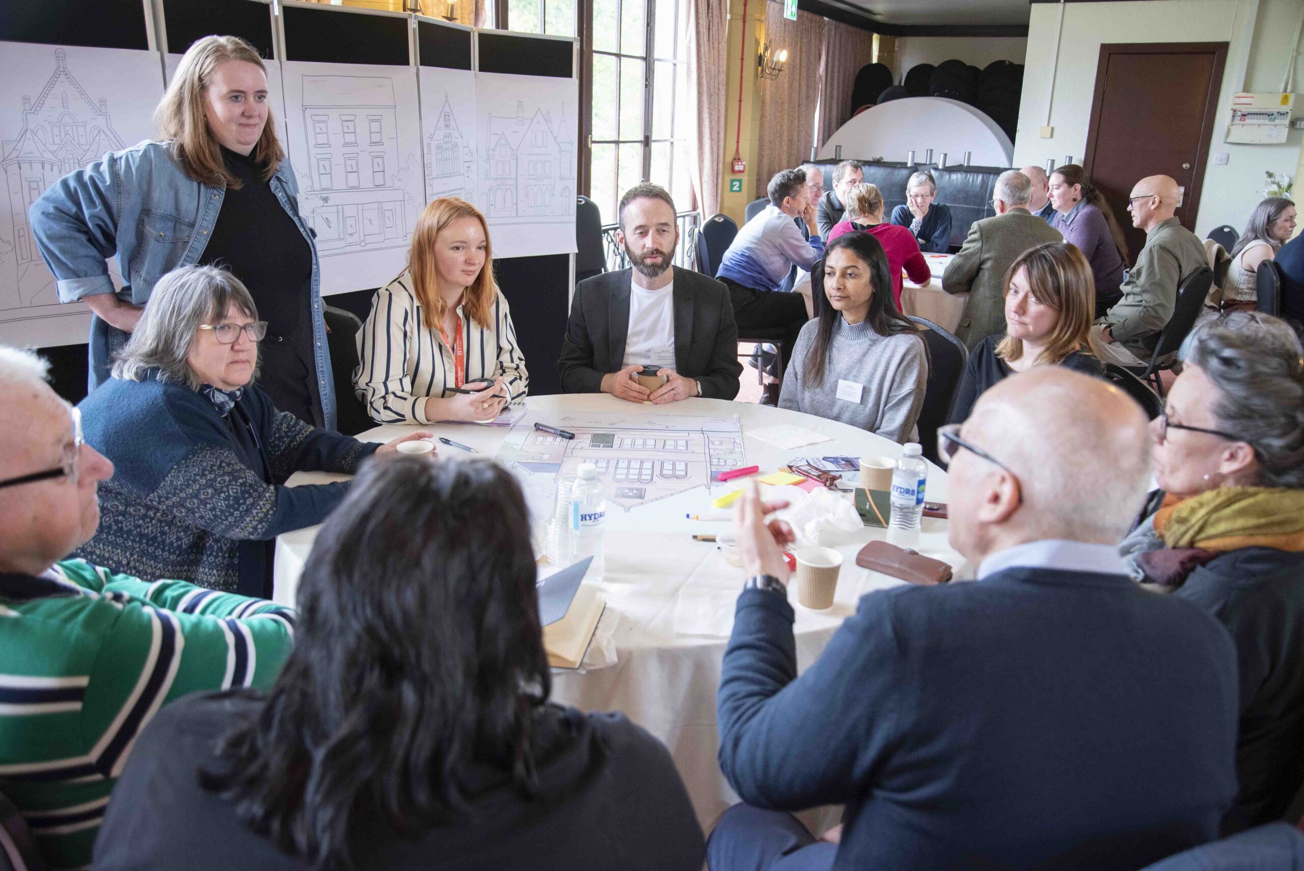 A group of people sit around a table, they are all involved in a discussion and look engaged.