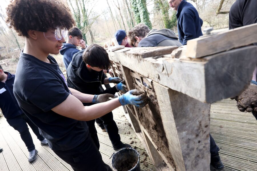 A photograph of students from Brighton Metropolitan College trying out wattle & daub.