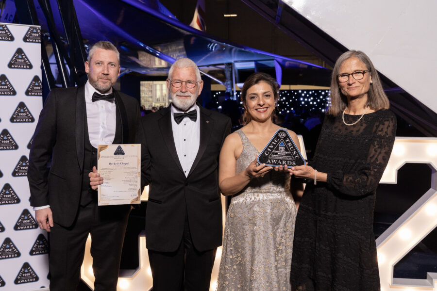 A photograph of two women and two men in evening dress. They hold the award and a certificate and are smiling at the camera.
