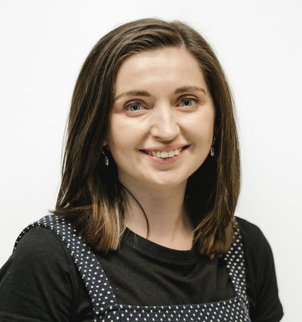 Beth looking at the camera directly and smiling against a white background