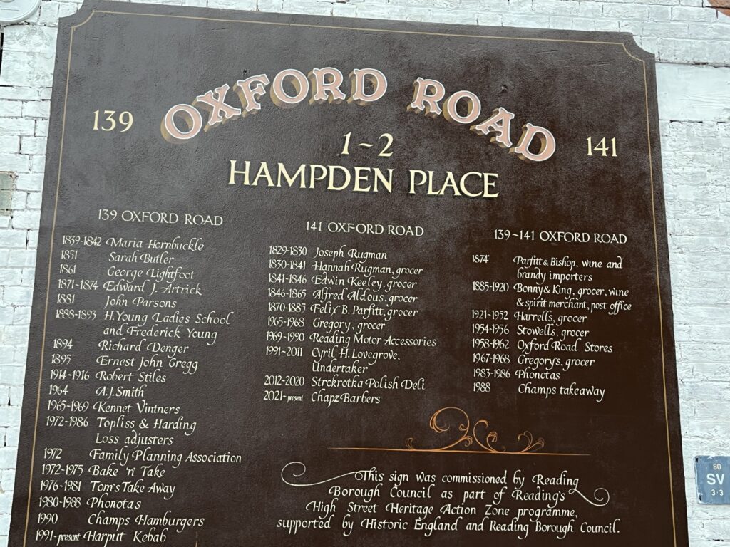 A photograph of the hand painted sign. It lists the names of individuals or organisations who lived in the buildings on the road from the Victorian period to the present day.