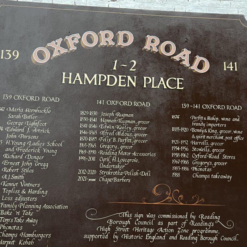 A photograph of the hand painted sign. It lists the names of individuals or organisations who lived in the buildings on the road from the Victorian period to the present day.