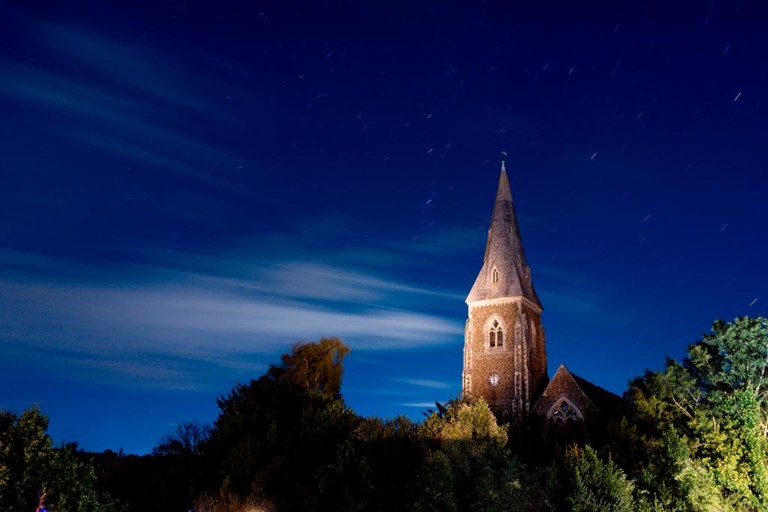 Burch Church Spire above the trees during a sunset.
