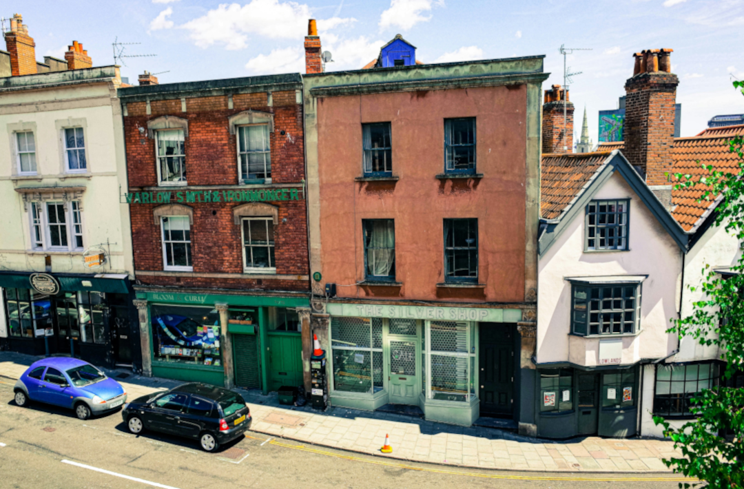Older shops on a hill with cars parked in front