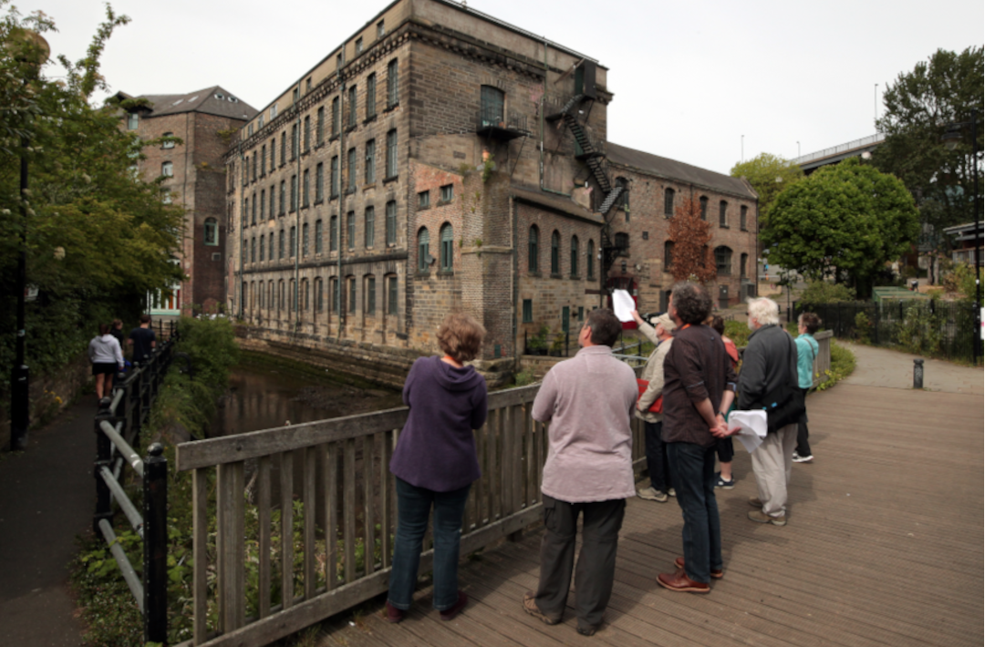 Group of people looking at an old mill building