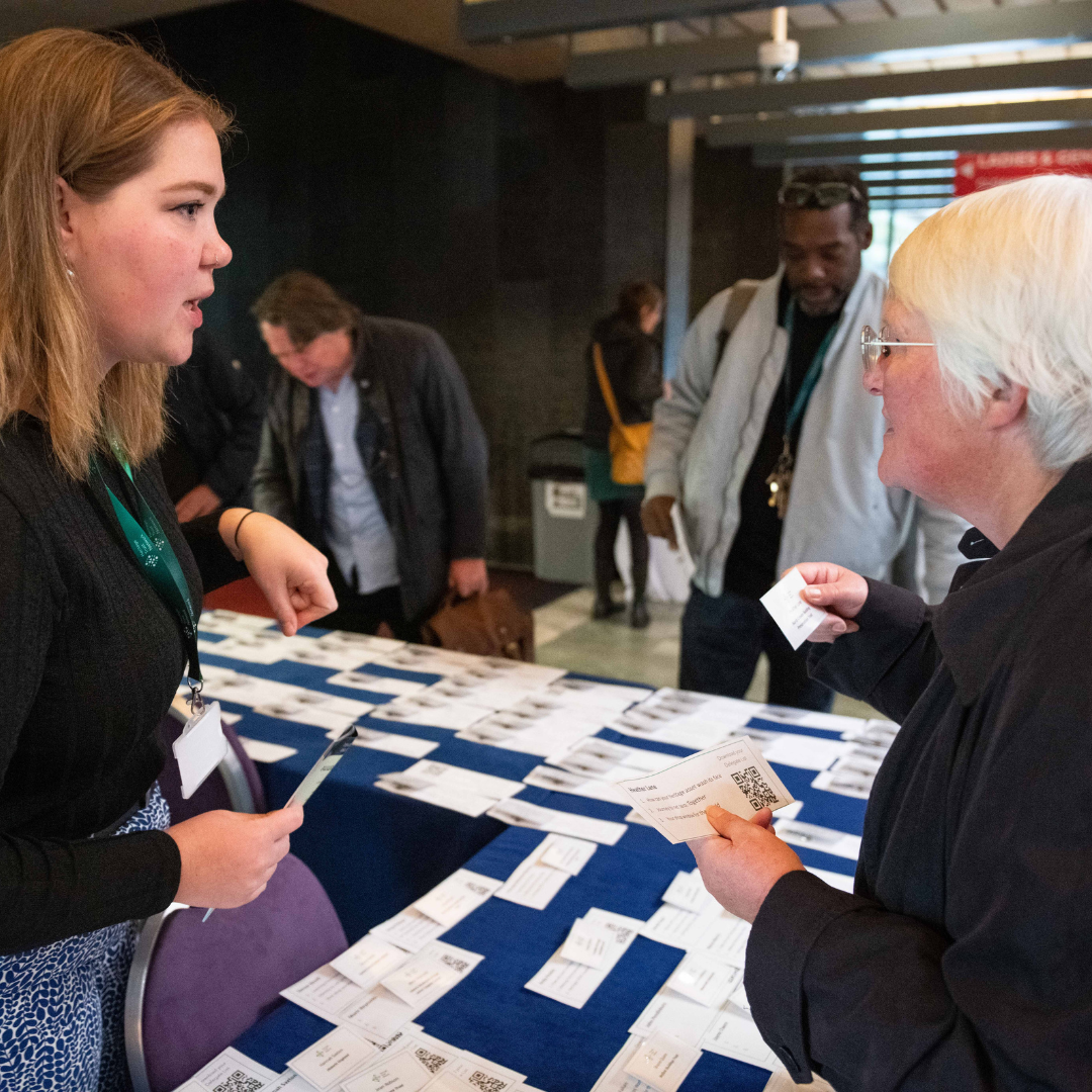 Photograph of a young woman helping conference delegate with an enquiry