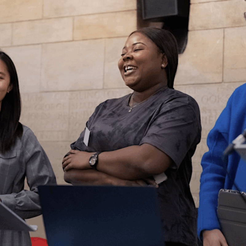 three young people stand on a stage behind a podium, they are smiling and giving a speech