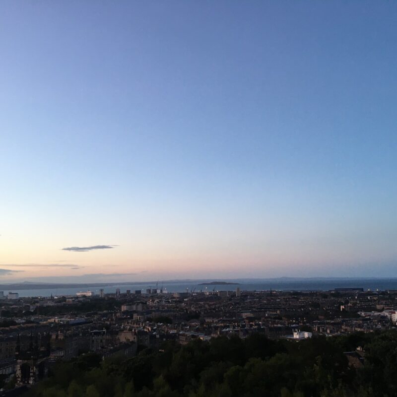 Photograph of Edinburgh skyline at sunset, with many historic buildings shown.