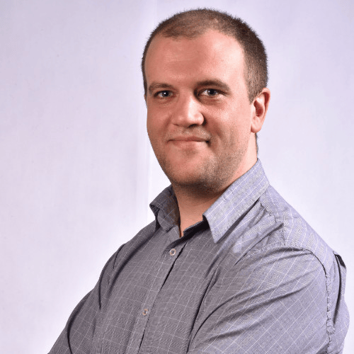 A man in a grey check shirt smiling at the camera