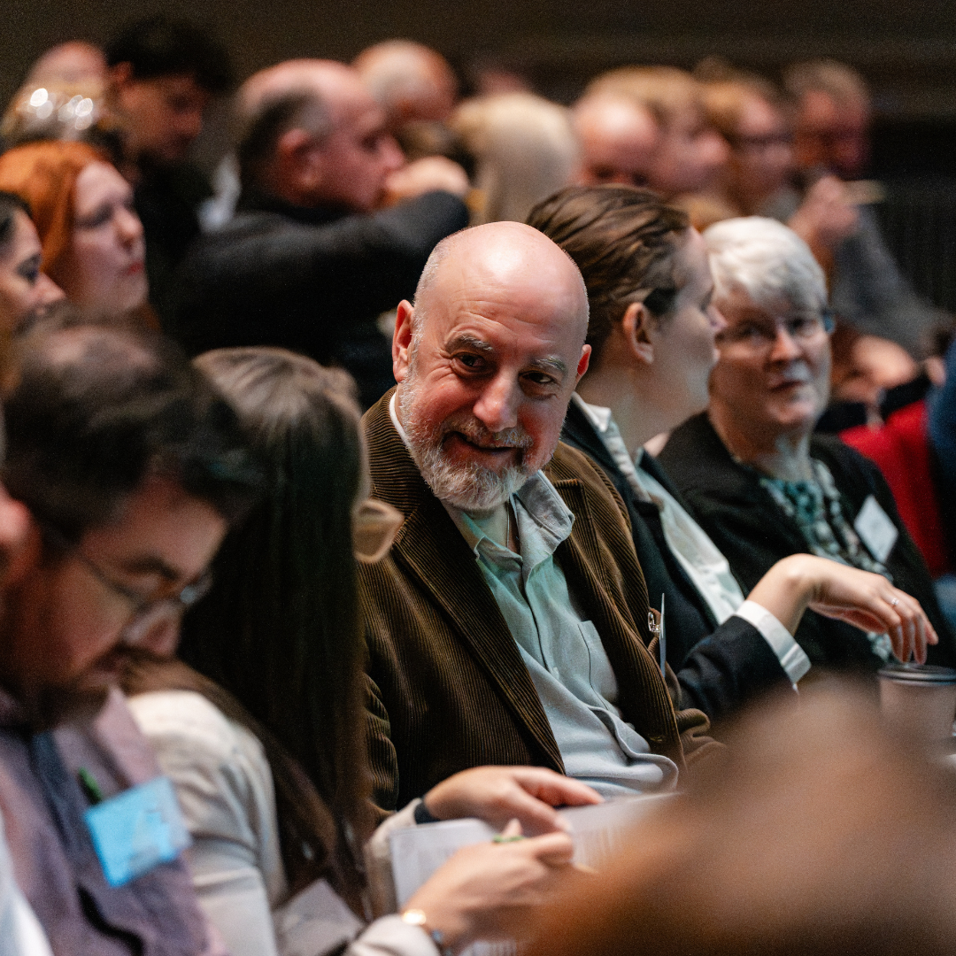 Photograph of conference delegates sat in rows, talking to one another