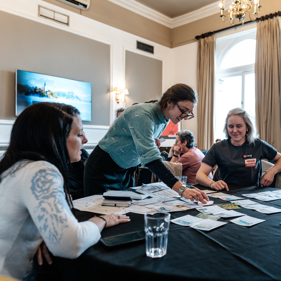 Photograph of a conference workshop, groups of people are working together to complete a task.